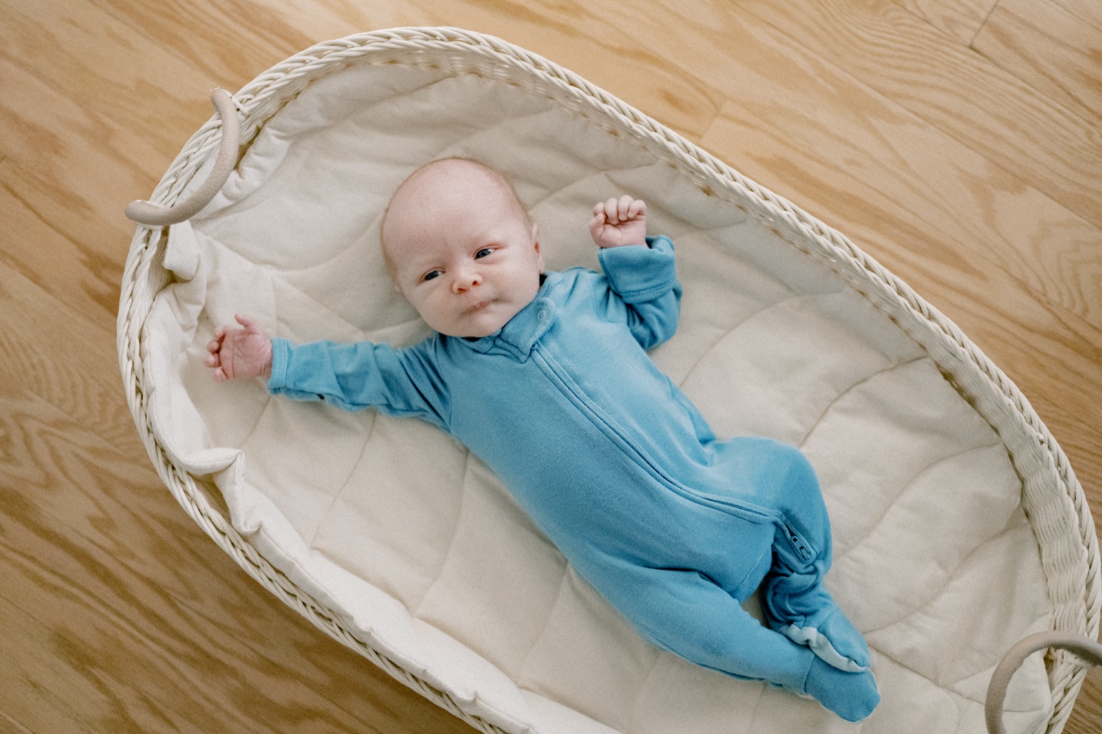 A calm, alert newborn resting in a bassinet